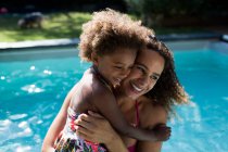 Happy mother and daughter hugging at sunny summer poolside — Stock Photo