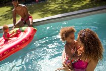 Familia jugando en la soleada piscina de verano - foto de stock