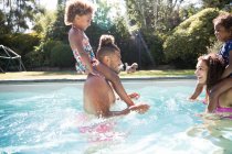 Семья играет в солнечном летнем бассейне — стоковое фото