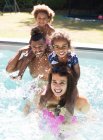 Retrato feliz família espirrando na piscina ensolarada verão — Fotografia de Stock