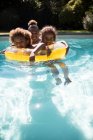 Portrait happy father and daughters in sunny summer swimming pool — Stock Photo