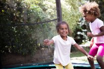 Happy sisters jumping on backyard trampoline — Stock Photo