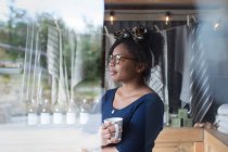 Proprietario di negozio femminile premuroso che beve caffè a finestra — Foto stock