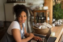 Propietaria de tienda femenina con confianza en retratos usando laptop en vivero de plantas - foto de stock