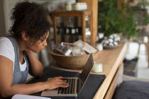Female shop owner using laptop at shop counter — Stock Photo