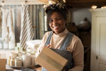 Portrait happy female shop owner with package — Stock Photo
