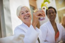 Mulheres idosas felizes amigos beber coquetel no pátio do hotel — Fotografia de Stock