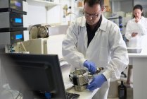 Мужчина-ученый, использующий оборудование на компьютере в лаборатории — стоковое фото