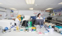 Científicas en máscaras faciales trabajando en laboratorio - foto de stock