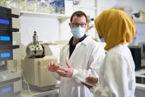 Cientistas em máscaras faciais falando em laboratório — Fotografia de Stock