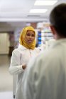 Femme scientifique dans le hijab parlant avec un collègue en laboratoire — Photo de stock