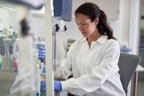 Фокусована жінка-вчена в лабораторному пальто працює в лабораторії — стокове фото
