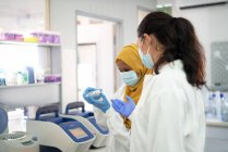 Жінки-вчені в масках обличчя з тримачем зразка в лабораторії — стокове фото