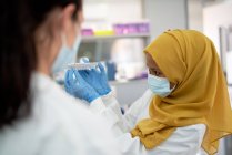 Femme scientifique en hijab et masque facial avec plateau à spécimens — Photo de stock