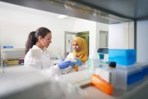Female scientists with pipette tray talking in laboratory — Stock Photo