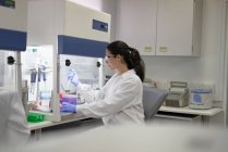 Científica femenina con pipeta trabajando en campana de humo en laboratorio - foto de stock