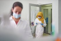 Cientista feminina em máscara facial e hijab usando tablet digital — Fotografia de Stock