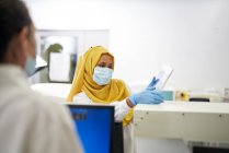 Femme scientifique en hijab et masque facial à l'aide d'une tablette numérique — Photo de stock