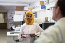 Женщина-ученый в хиджабе разговаривает с коллегой в лаборатории — стоковое фото