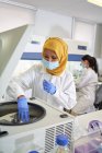 Scienziata in hijab e maschera facciale con centrifuga in laboratorio — Foto stock