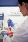 Female scientist using pipette tray at laboratory fume hood — Stock Photo