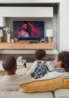 Famiglia guardando la TV sul divano del soggiorno — Foto stock