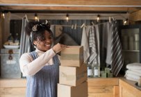 Sorridente proprietaria di un negozio femminile con pile di scatole di cartone — Foto stock