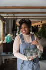Portrait happy female shop owner holding glass plant holder — Stock Photo