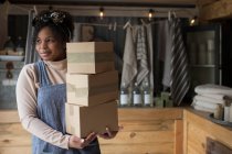 Porträt selbstbewusste Ladenbesitzerin mit einem Stapel Kartons — Stockfoto