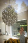 Senior woman talking on smart phone in kitchen with chandelier — Stock Photo