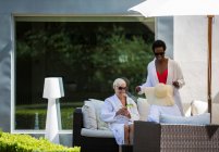 Senior women friends relaxing in spa bathrobes on luxury patio — Stock Photo