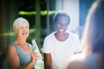 Щасливі старші жінки друзі сміються над сонячним літнім патіо — стокове фото
