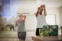 Senior women friends exercising at laptop in dining room — Stock Photo