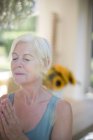 Спокойная пожилая женщина медитирует с закрытыми глазами — стоковое фото