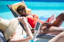 Mulheres idosas felizes amigos relaxante e banhos de sol na piscina ensolarada — Fotografia de Stock