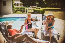 Mulheres idosas amigas bebendo champanhe e tomando sol no pátio ensolarado — Fotografia de Stock