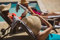 Senior women friends sunbathing at sunny summer poolside — Stock Photo