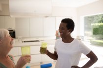 Glückliche Seniorinnen trinken nach dem Sport zu Hause Wasser — Stockfoto