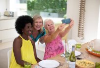 Happy senior women friends taking selfie at luncheon — Stock Photo
