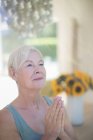 Mujer mayor serena meditando con las manos apretadas - foto de stock