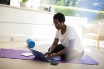 Femme travaillant et faisant de l'exercice sur tapis de yoga à la maison — Photo de stock