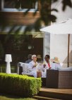 Старшие подруги отдыхают в спа-халатах на солнечном патио отеля — стоковое фото
