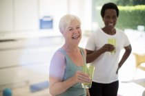 Happy senior women friends drinking water after workout at home — Stock Photo