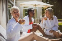 Ritratto felici amiche anziane rilassanti sul patio soleggiato dell'hotel — Foto stock
