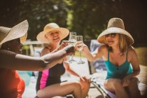 Senior women friends drinking champagne at summer poolside — Stock Photo