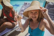 Portrait happy senior woman drinking champagne at sunny poolside — Stock Photo