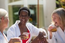 Happy senior women friends enjoying cocktails on sunny patio — Stock Photo
