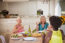 Amici anziani che si godono il vino bianco con il pranzo a tavola — Foto stock
