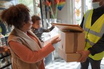 Mother and baby daughter receiving packages from delivery person — Stock Photo