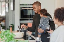 Glückliches Paar mit kleiner Tochter kocht Abendessen in Küche — Stockfoto